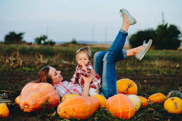 mother and daughter lie between pumpkins