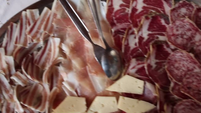 Hand serving a mixed salami dish