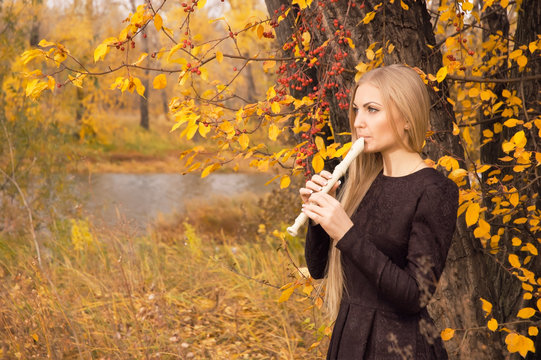 Beautiful Young Blonde Woman Playing Flute Recorder In Autumn Forest