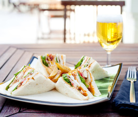 Club sandwich with french fries and a beer