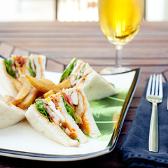 Club sandwich with french fries and a beer