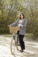 Young female walking with bicycle in a park