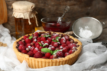 Tart with fresh raspberries, on wooden background