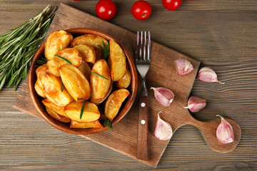 Baked potato wedges on wooden table, top view