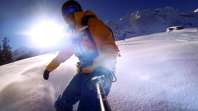 Man riding on snowboard with selfie stick in his hand , slow motion shot