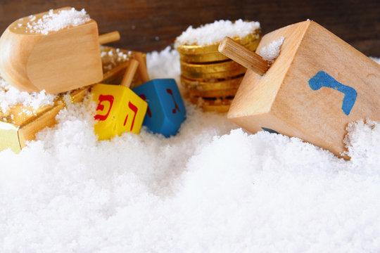 image of jewish holiday Hanukkah with wooden colorful dreidels (spinning top) over december snow. copy space
