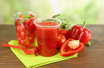 Vegetable and fruit  salad and healthy fresh drink in plastic cups on wooden background. Colorful diet concept