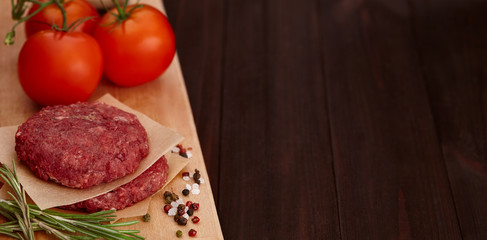 Raw meat for burgers with spices on wooden board