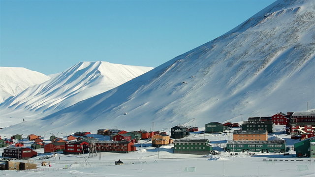 Small town Longyearbyen among snow-capped mountains of the Norwegian archipelago of Svalbard in early spring.