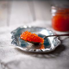 Salmon red caviar in a glass jar and spoon
