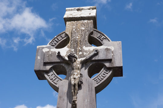Crucifix on a Celtic Cross Gravestone, with blue sky above.