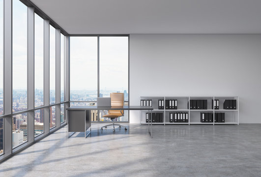 A workplace in a modern corner panoramic office with New York city view. A black desk with a laptop, brown leather chair and a bookshelf with black document folders. 3D rendering.