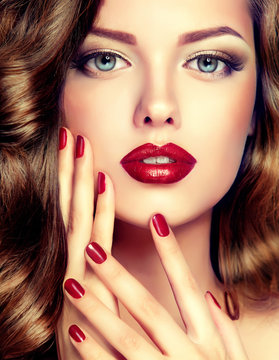 Beautiful model with curly hair and red manicure closeup . fashion trend image ,the girl with blue eyes , fashion makeup and red nails