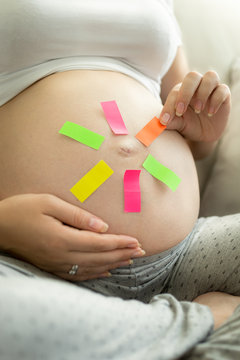pregnant woman tearing off memo sticker from belly