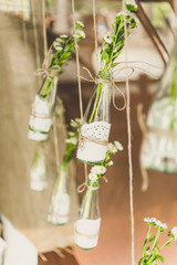 toned photo of decorated bottles with flowers hanging on twine