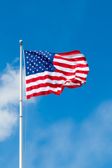 American flag waving against blue sky. Copy space.