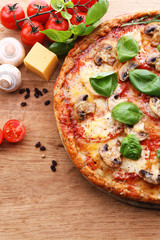 Tasty pizza with vegetables and basil on table close up