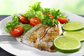 Dish of fish fillet with salad and lime on plate close up