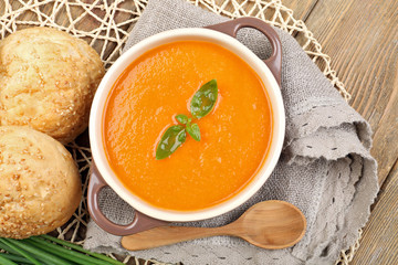 Carrot cream-soup with buns on table close up