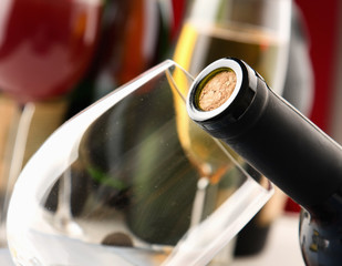 closeup of a bottle with a cork, bottles and glasses on the