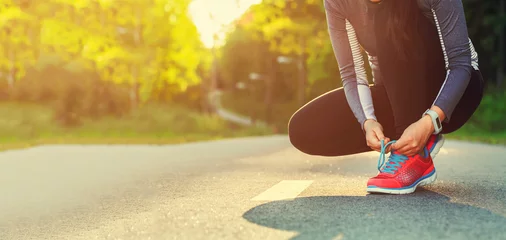 Abwaschbare Fototapete Joggen Läuferin binden ihre Schuhe Vorbereitung für ein Joggen
