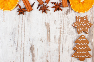 Fresh baked decorated gingerbread with spices on old wooden background, christmas decoration