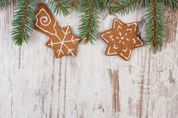 Fresh baked decorated gingerbread and spruce branches on old wooden background, christmas time