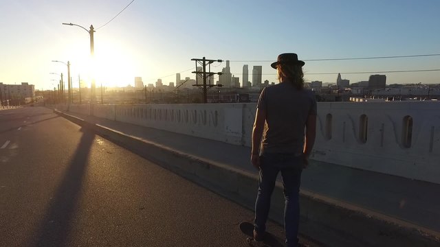 Skateboarder coasts cruises downhill los angeles city street relaxed urban downtown sunset hipster exercise transportation 