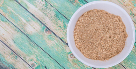 Lemongrass powder in a white bowl over wooden background