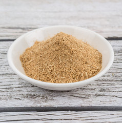 Lemongrass powder in a white bowl over wooden background