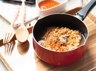 Instant noodles in frying pan on wood