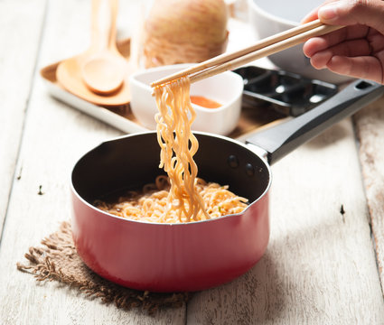 Instant noodles in frying pan on wood