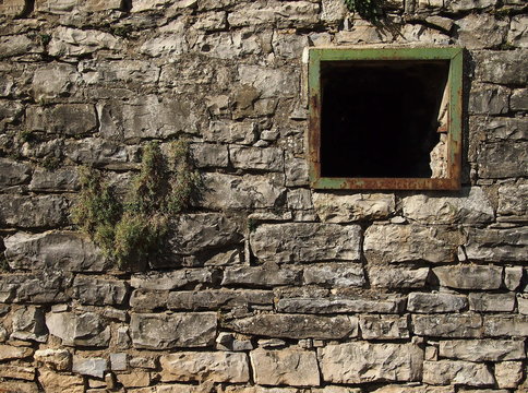 Old stone wall with a broken windows.