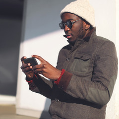 Lifestyle portrait fashion young african man using smartphone in