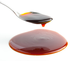 Pouring Soy Sauce on spoon isolated on white,Selective focus