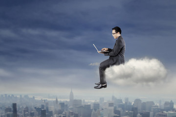 Fototapeta na wymiar Businessman using laptop on the cloud