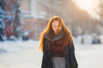 Fototapeta na wymiar Positive redhead girl on the sun in frozen winter day