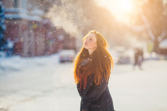 Positive redhead girl on the sun in frozen winter day