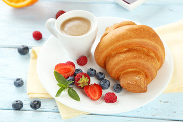 Fresh tasty croissants with berries on blue wooden background