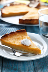 Tasty pumpkin pie on plate on a blue wooden table