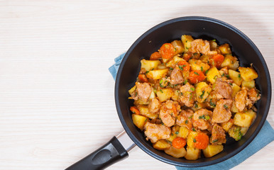 stewed meat with potatoes, onion and carrot in a frying pan
