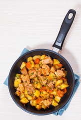 stewed meat with potatoes, onion and carrot in a frying pan