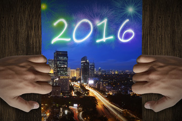 Hand open wooden door to the city that celebrate new year 2016