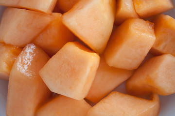 closeup melon slice in white dish with wood table background