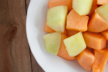 closeup melon slice in white dish with wood table background