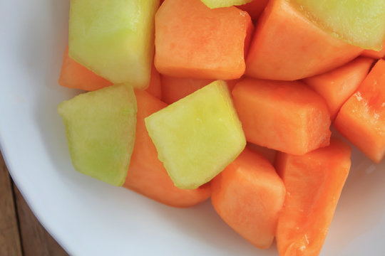 melon slices in white dish on wood table