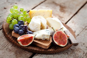 Cheese platter: variety of cheeses on wooden plate with fruits