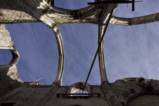 Looking up at the roofless Carmo Convent in Lisbon, facing the sky