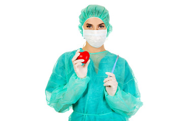 Young female cardiologist surgeron holding heart and scalpel