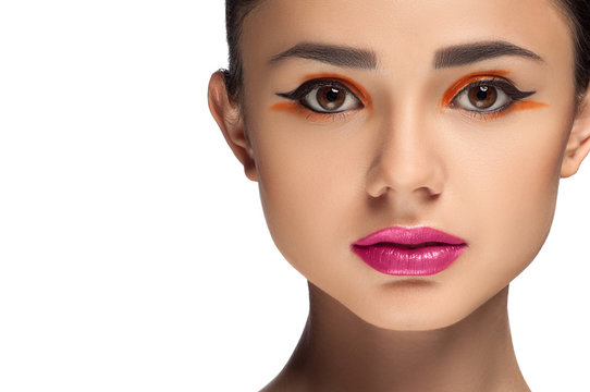 High fashion look, closeup beauty portrait of beautiful young woman model with bright makeup, perfect clean skin and colorful red pink lips and orange eyeshadow. 